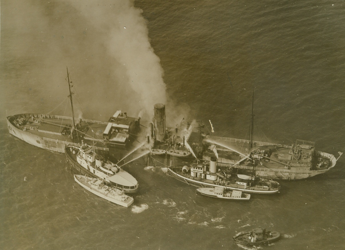 NORWEGIAN FREIGHTER BOUND FOR ENGLAND BURNS, 8/81940  NEW YORK CITY—Fireboat and Coast Guard vessels fighting fire aboard the Norwegian freighter Lista, 3,671 tons, as it turned about in outer New York Harbor and headed back to port. The ship later went aground in flames and was abandoned by its crew of 28. The ship carrying a heavy cargo for Britain, went aground near West Bank Light, with the fire out of control. Credit: Acme;