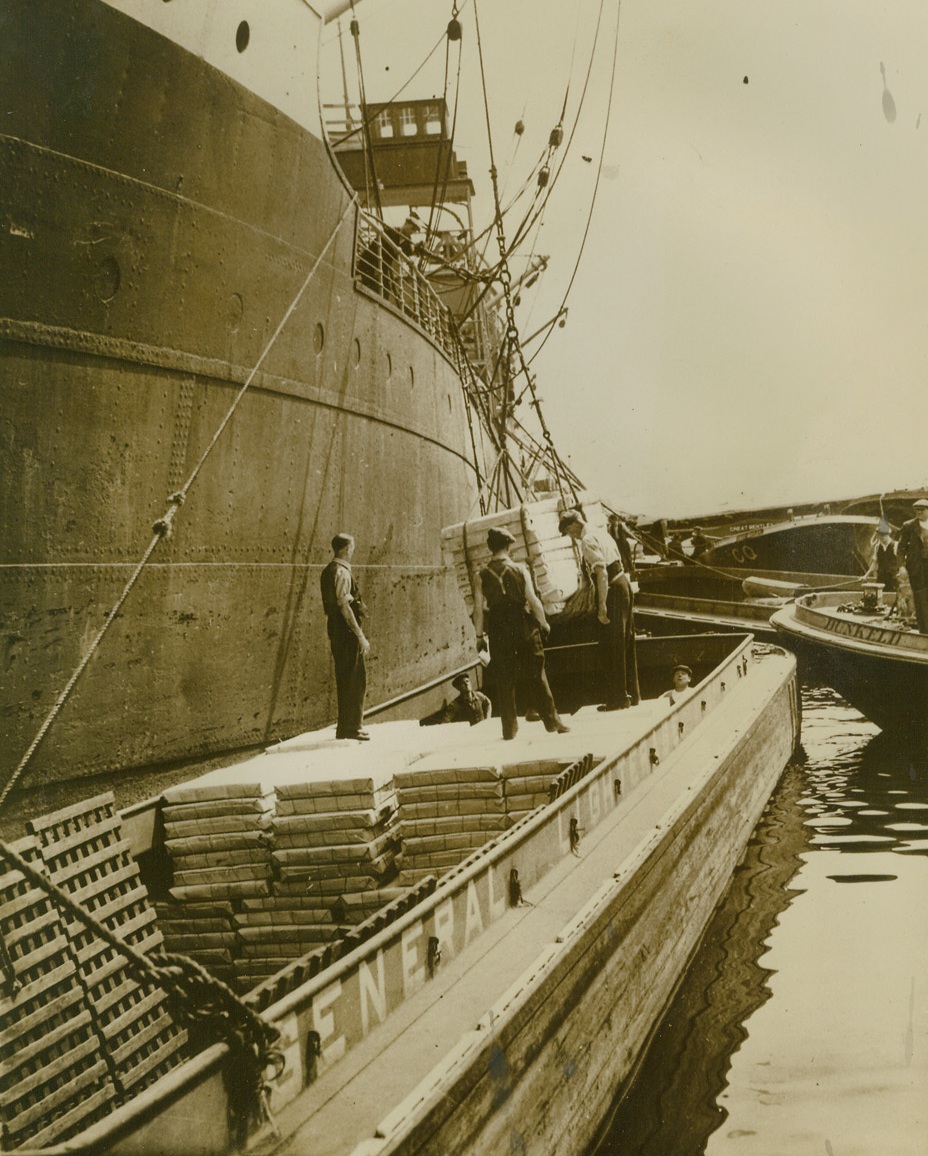 BUSINESS AS USUAL AT THE PORT OF LONDON, 8/31/1940  LONDON – Denying German reports that the port of London was put out of operation by smashing Nazi air raids, the British censor released this picture, showing activity “going on as usual” at the port as paper is being loaded for New Zealand.Credit: Acme;