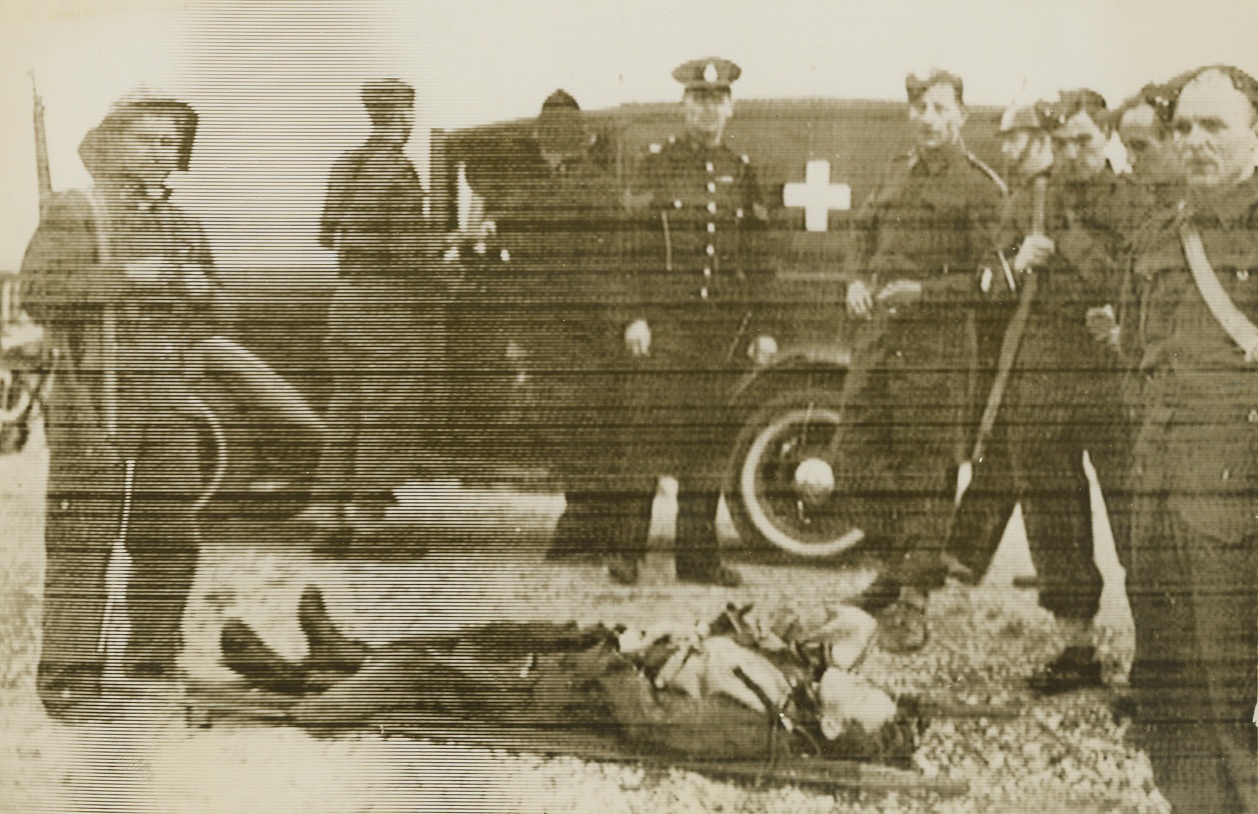 FALLEN NAZI, 9/16/1940  ENGLAND – British soldiers and police stand by an injured Nazi airmen, shot down in a battle over the South coast of England.  Photo sent from London by Western Union cable Sept. 16th. Credit: Acme;