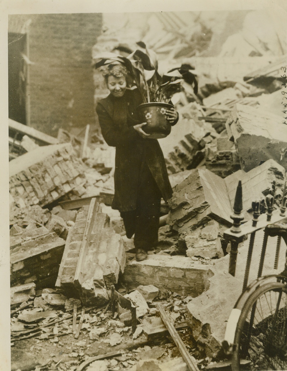 Saves Prized Possession After Air Raid, 10/23/1940  LONDON, ENGLAND -- Smiling, despite the terror from the skies, this London woman makes her way through the bomb-debris of a London street carrying her prized possession, a potted plant, which she saved from the ruins of her home. Credit: (ACME);