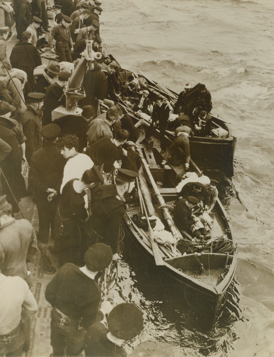 Rescue’s End, 11/14/1940  England – Survivors of a torpedoed British Merchant Ship shown alongside a Canadian Destroyer, upon arrival at an unnamed English port. The ship’s surgeon and the crew members may be seen preparing injured for hoisting aboard while rescued survivors mingle with sailors on deck. The Canadian warship rescue survivors. Credit: ACME;