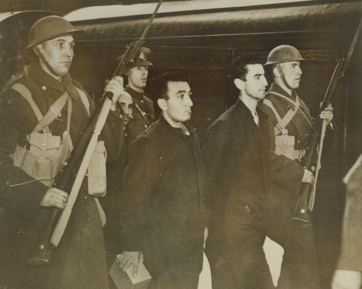 First Italian Submarine Prisoners in England, 11/26/1940  LONDON, ENGLAND—A study of two of the Italian sailors of the first group of Italian submarine prisoners in England as they are taken to a train under an escort with fixed bayonets. Credit: ACME.;
