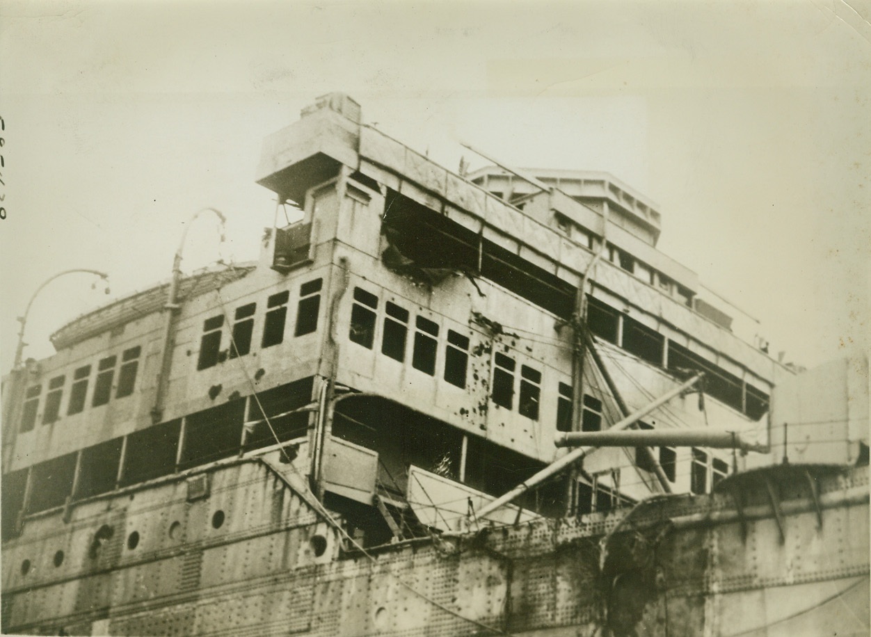 CARNARVON CASTLE SHOWS SCARS OF BATTLE, 12/13/1940  MONTEVIDEO, URUGUAY – One funnel shot away altogether and with her hull and superstructure carrying marks of direct shell hits and flying shrapnel, the British Merchant Cruiser “Carnarvon Castle” is shown as she limped into port after a running battle at sea with a German Raider. At top is shown where a shell struck the promenade deck just below the bridge, while at lower right a gaping wound marks a direct hit by another shell. Shrapnel marks are profuse. Credit: OWI Radiophoto from ACME;