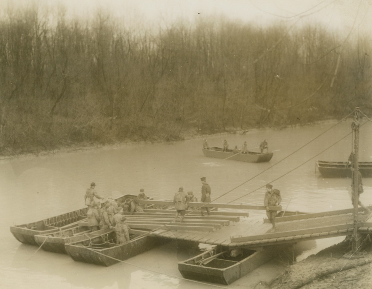Army’s Armored Division Crosses River, 12/13/1940  Fort Knox, KY—Despite rain and mud, engineers of the First Armored Division erect a pontoon bridge during river crossing exercises, December 13. 11-ton tanks and armored cars safely crossed the river on the completed project. Other machines were ferried across on pontoon boats. Credit: ACME.;