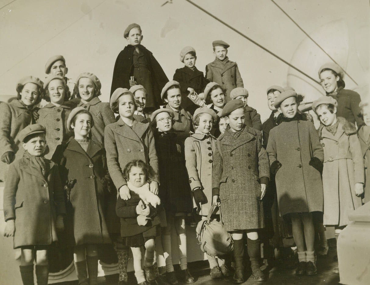 American Committee Brings Over 25 Refugees, 12/23/1940  Jersey City, N.J.—Children of six nationalities were among the 25 arriving on the American export liner Excambion from Lisbon through the efforts of the American Committee for the Care of European Children and the Unitarian Service Committee as the first group to be brought to this country under the Committee’s sponsorship. French, Russian, Austrian, German, Polish, and Czecho-Slovakian make up the group, shown here as they entered New York Harbor aboard the ship. Credit: ACME.;