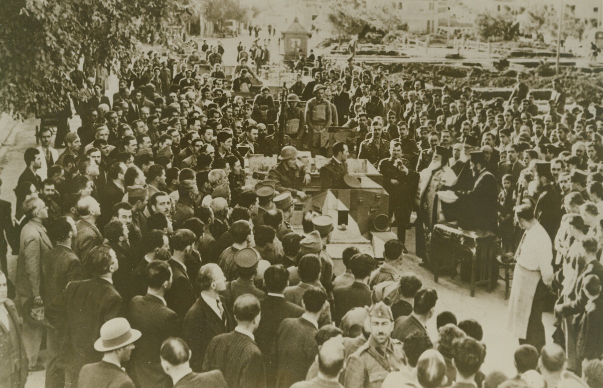 GREEK BISHOP BLESSES BRITISH TANKS, 12/26/1940  KHANIA, CRETE—The Bishop of Khania (Canea), Greek town on the Isle of Crete gave his official blessing to British men and equipment arriving to help his countrymen in their struggle against the Italians, and here he is shown blessing the Bren gun carriers and light tanks in the presence of soldiers and townspeople. Each soldier kissed the cross and received the Episcopal benediction, according to British-censored caption accompanying this photo. Credit: Acme;