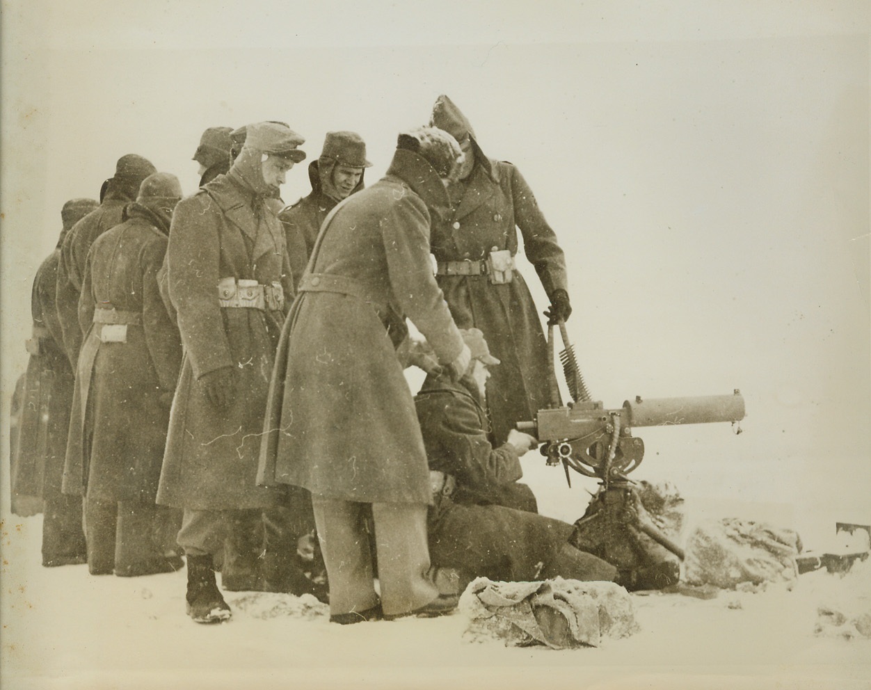 U.S. Army Trains for Winter Fighting, 12/28/1940  PLATTSBURG BARRACKS, N.Y. – Army officials haven’t overlooked the phase of winter fighting. At Plattsburg Barracks, N.Y., a group of recruits look on as another fires a machine gun in subzero temperature along the shore of Lake Champlain. The instructor (directly behind the gunner) is Lieut. Albert R. Cupello, of the 26th Infantry. Credit: (ACME);