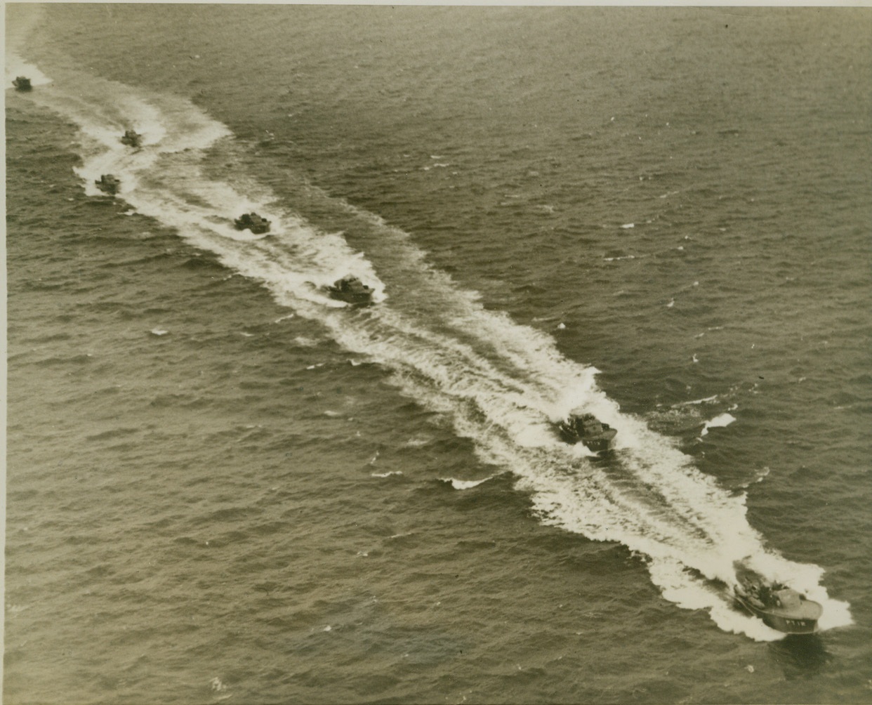 MOTOR TORPEDOBOAT FLOTILLA HEADS SOUTH, 1/13/41  NEW YORK CITY – An airview of the flotilla of eleven of the Navy’s motor torpedoboats, detailed for duty in southern waters “somewhere off Key West, Fla.,” as the deadly and swift little craft raise foaming wakes in the waters of Lower New York Bay with a fast start to their new stations. These craft, which can do over 70 miles per hour, are manned by 20 officers and 150 men, specially selected for the assignment. The flotilla is commanded by Lieutenant Commander Earl S. Caldwell. Credit: OWI Radiophoto from ACME;