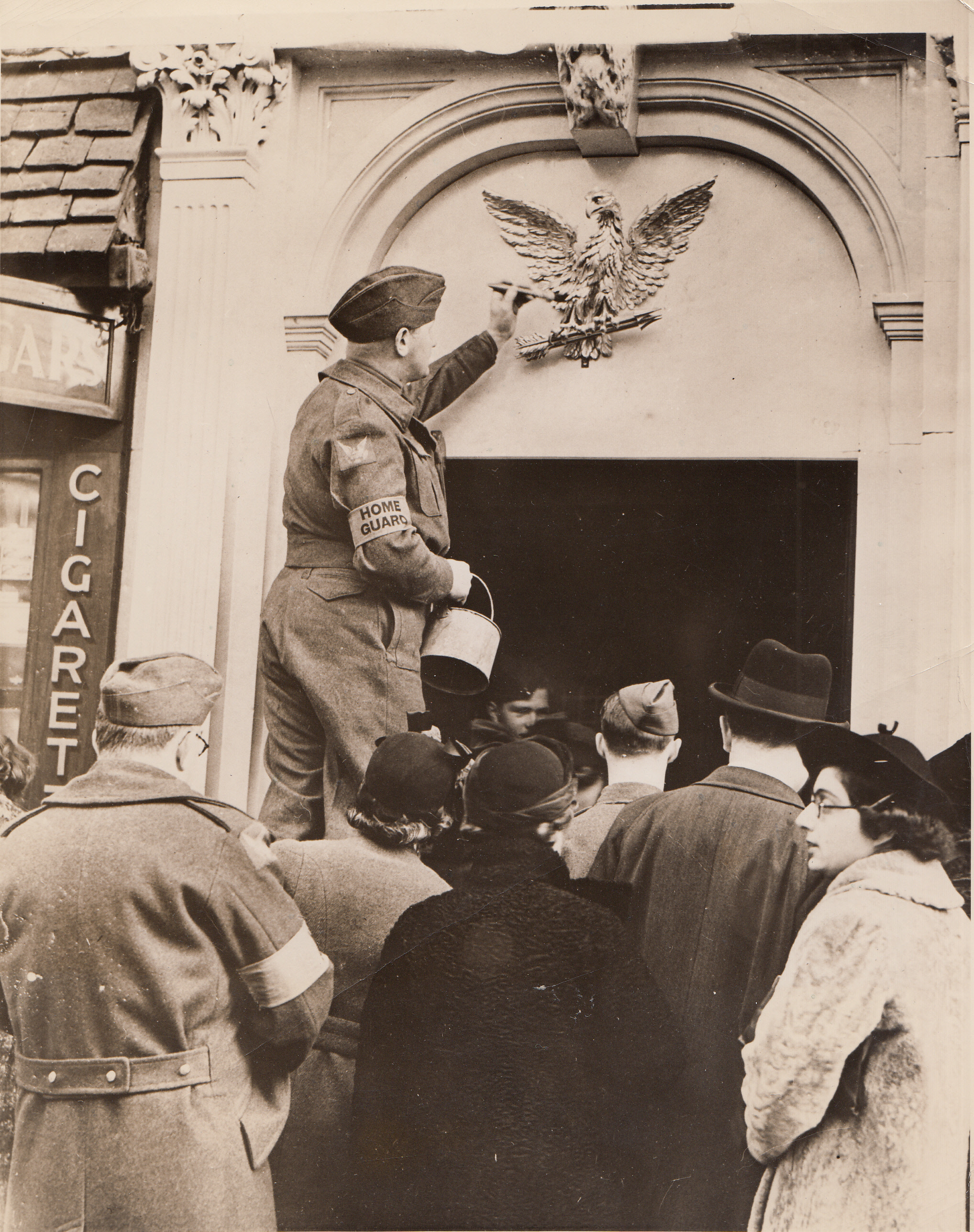 NEW CLUB FOR AMERICANS, 1/14/41  LONDON: - A member of the American mechanized corps serving with the British, gilds the eagle over the entrance to the American Eagle Club after the club was formerly opened, Dec. 17.  The club will be used as a center for all Americans serving with the British forces.;