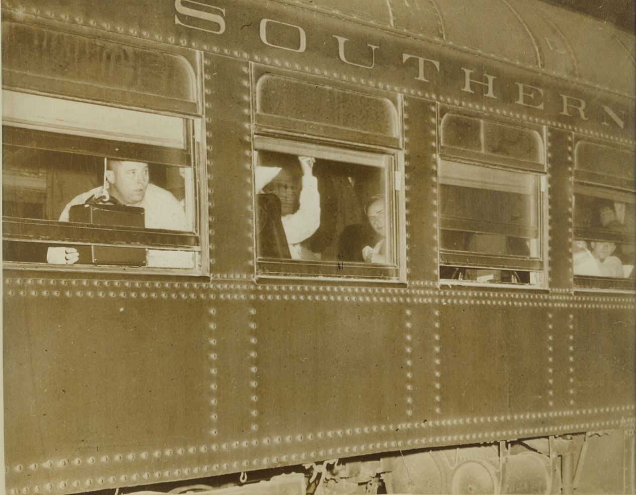 CREW OF SCUTTLED GERMAN LINER INTERNED, 2/1/41  EL PASO, TEX. – Members of the crew of the scuttled German liner Columbus peek from windows of their closely guarded railroad car while enroute for Fort [illegible], in southern New Mexico, where they will be interned for the duration of the European war. Credit: ACME;