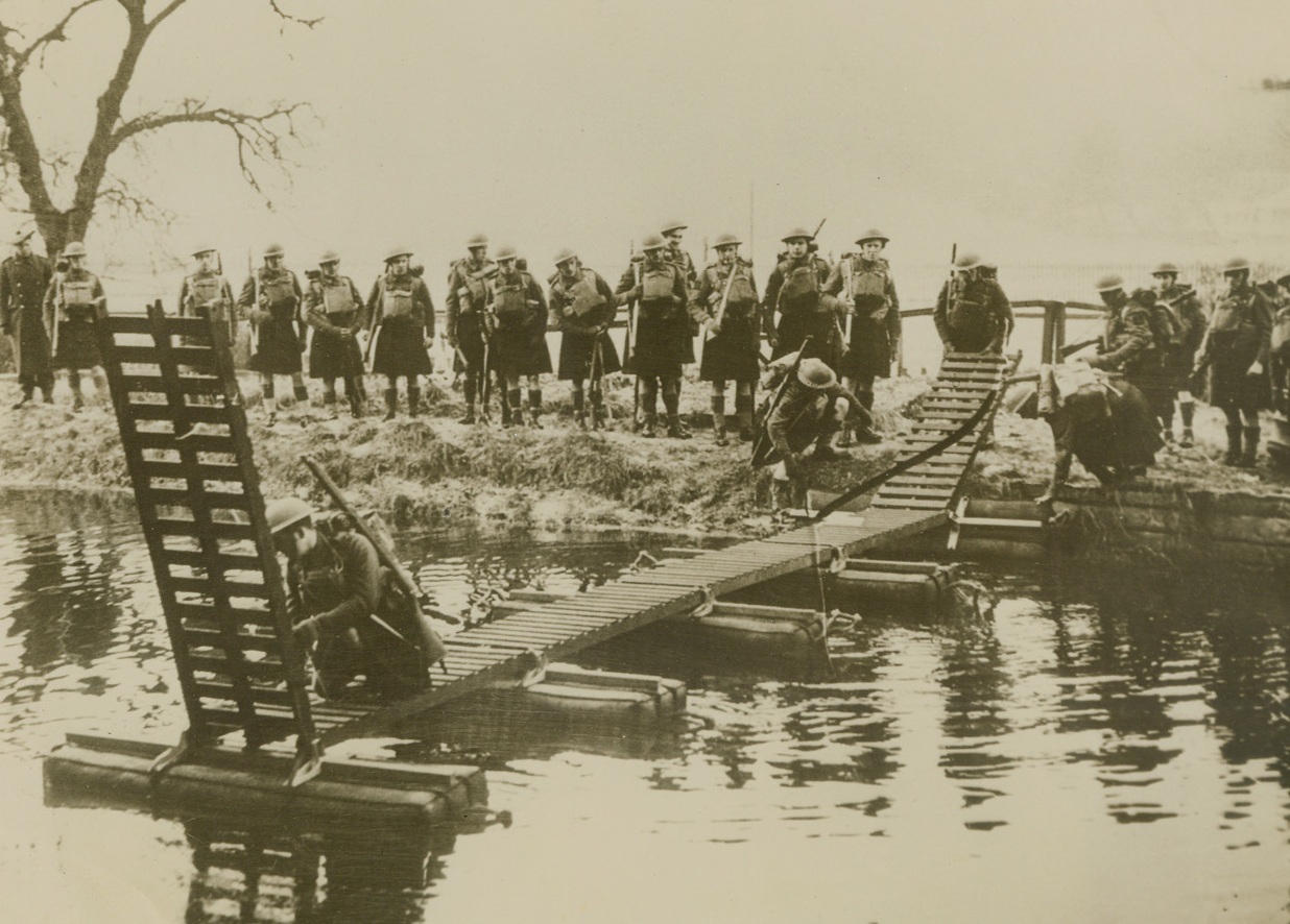 No Title, 2/5/41  Scotland—Members of a battalion of the Queen’s own Cameron Highlanders, training in the shows of their native Scotland at the Infantry Training Center, construct a Kapok bridge across a river. The Highlanders are training for the invasion, but the caption on this official British picture does not state if the training is for a defense against invaders or for an invasion by the British forces. Credit: ACME. Passed by British censor—via Clipper.;