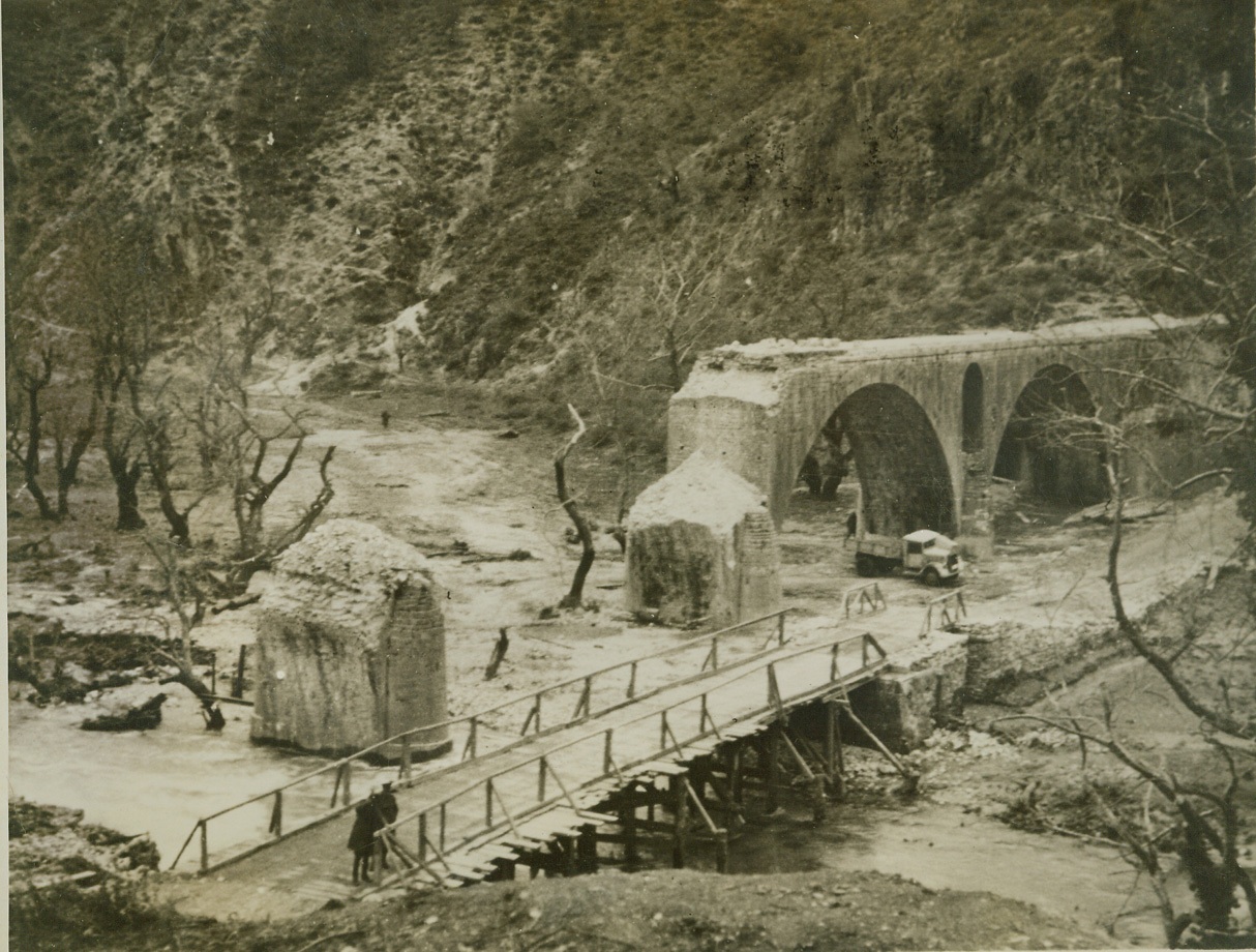 TO SLOW UP THE ENEMY, 2/13/41  This is all that remains of a stone bridge that was once a sturdy highway across the Albanian River. Italian troops, retreating before a Greek advance, blew up the structure. Credit: ACME;