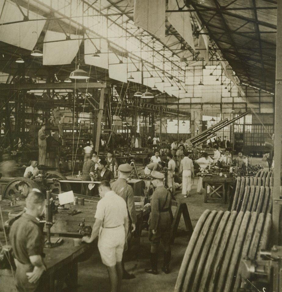 Turning Out Guns for the East Indian Army, 2/17/41  Bandoeng, Java – This Army ordnance shop in Bandoeng, Java, is busily turning out coast artillery pieces and range finding instruments in the Netherlands Indies great rearmament program.  In the background is a standard Army 8 centimeter anti-aircraft gun.  The Dutch colonial government is determined that the Netherlands Indies shall not fall prey to unpreparedness and is building up its Armed Forces with the utmost speed.Credit Line (ACME);