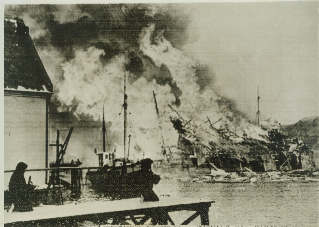 Flames and smoke, 2/1/41  LONDON -- Flames and smoke shoot skyward from an oil factory set afire by British soldiers who invaded Vaagso in German-occupied Norway on December 27. In the foreground the British hold a jetty against snipers. British sources stated that Commandos took part in the raid. Credit: (ACME Cablephoto);