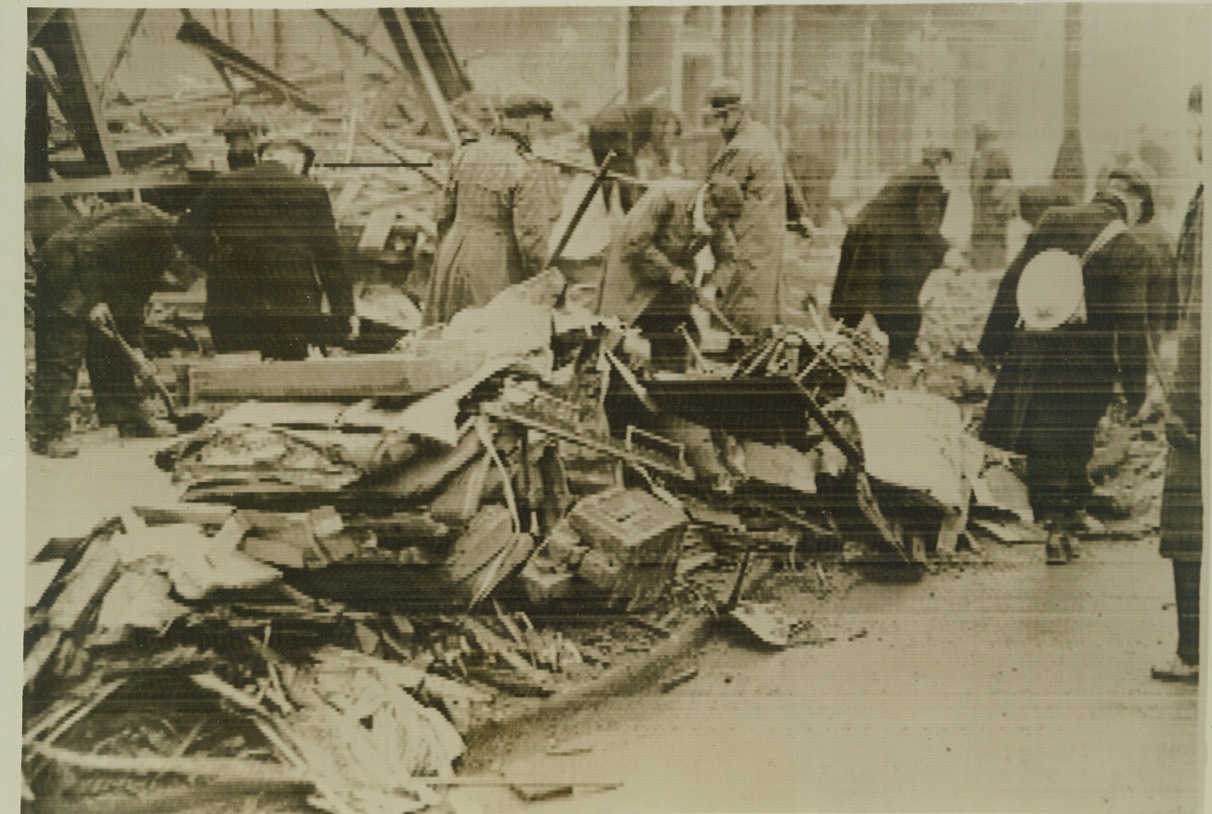 Many Killed as Bomb Strikes London Bus, 3/16/41  LONDON, ENGLAND -- Rescue workers frantically search the ruins of a bus struck by a German bomb during the early morning air raid of Mar. 16th for the bodies of passengers killed. "A considerable number" of persons perished when the bomb struck, according to the British censor-passed caption. This picture was flashed to New York from London by cable. Credit: (ACME cablephoto);