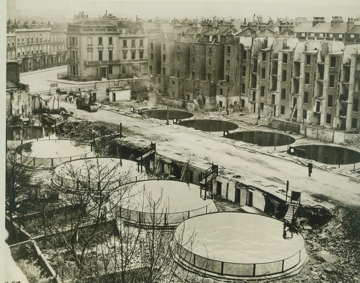 Emergency Water Tanks Built in London, 12/9/41  LONDON, ENGLAND -- Nine huge water tanks built on the sites of bomb-destroyed buildings in London, for use of firefighters, should water mains fail. In some instances, the basements of destroyed buildings are filled with water for the same purpose, after debris is cleared away. Note shells of gutted dwellings in right background. This picture just arrived here by Clipper. Credit: (ACME);