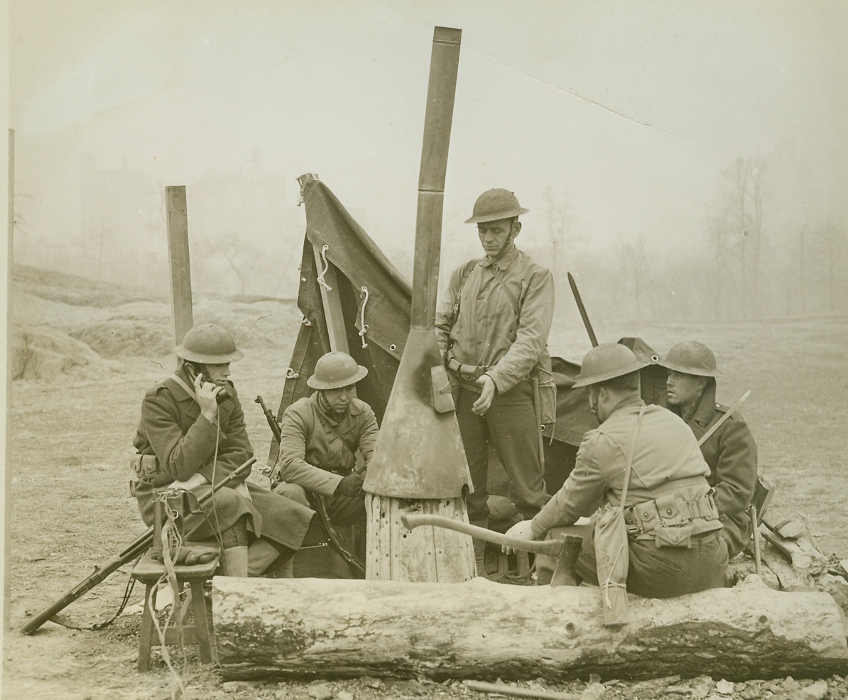 Air Raiders will find New York City Prepared, 12/29/41  NEW YORK, N.Y. – Should any enemy aircraft attack New York City, they will find it prepared. Photo above shows anti-aircraft gun crew around stove in a city park, where they are on 24-hour watch. Note signalman at field telephone, which is connected with headquarters and over which any air raid alarm would be sent. Because of Army censorship background and all identifying marks have been blacked out so that location of this emplacement will not be revealed.  Credit: (ACME);