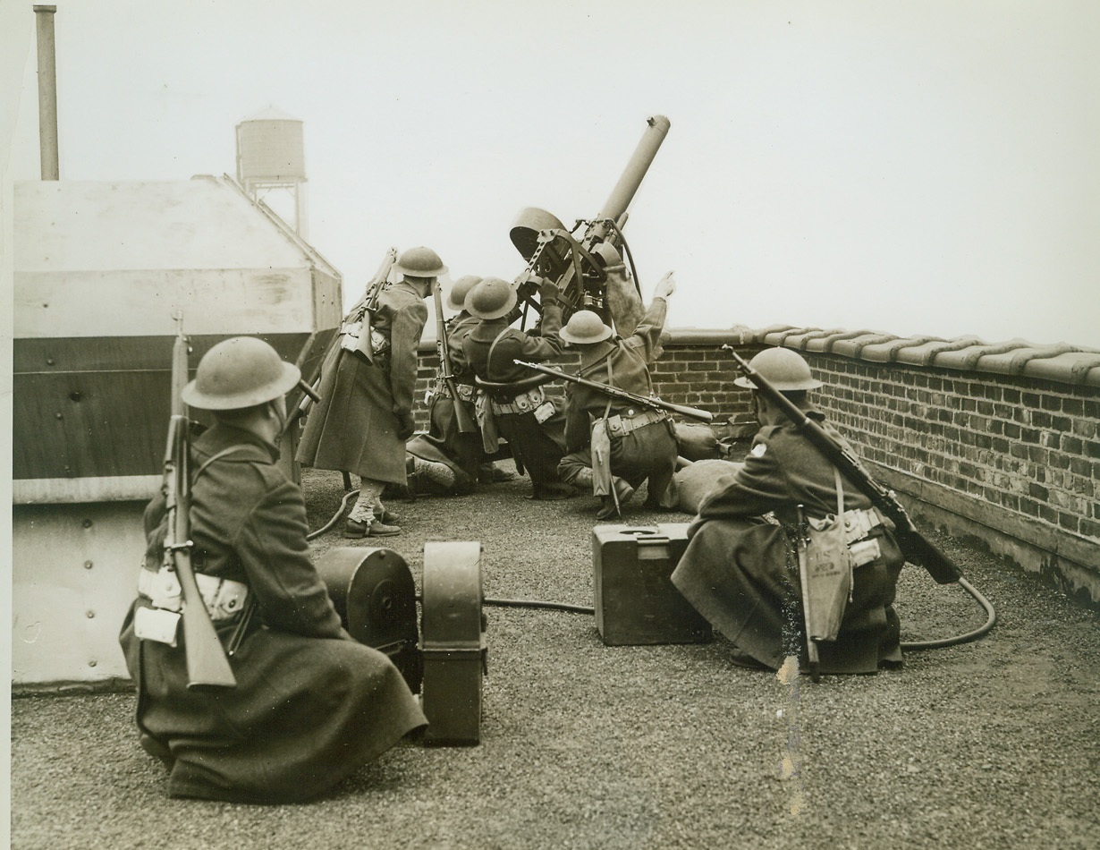 Anti-Aircraft Guns Ready to Protect New York, 12/29/41  NEW YORK, N.Y. – Aircraft defenses have been set up in New York City and anti-aircraft crews are on 24-hour watch for enemy air raiders. Photo above shows anti-aircraft gun emplacement on roof of skyscraper, with crew on practice “alert” pointing it at an imaginary enemy plane. Because of Army censorship background and identifying marks have been blacked out so that location of this emplacement will not be revealed. Credit: (ACME);