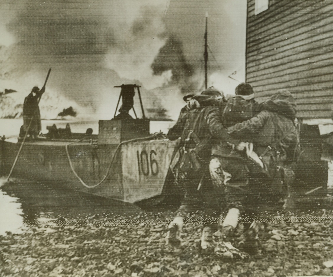 EVACUATING WOUNDED FROM NORSE BASE RAZED BY BRITISH, 12/31/41  VAAGSOE, NORWAY—British commandos, in a surprise down landing, Dec. 27, on the small German-occupied port of Vaagsoe, killed, wounded or took prisoner almost the entire garrison of upward 200 men, ‘blitzed’ all the industrial plants, dynamited and spiked all the coastal guns that protect this important assembly place for Norwegian coastal convoys. Shown in this radiophoto just received from London is the evacuation of British wounded to invasion barge during raid. Credit: Acme Radiophoto;