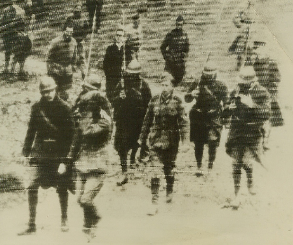 French Bring Back Prisoners on Western Front, 11/29/1939. Two German prisoners captured by French soldiers on Western front are marched to the French Field Intelligence Office for questioning. Prisoner in foreground is camera shy, hides his face. Second prisoner, center, doesn’t mind being photographed. Credit: ACME.;